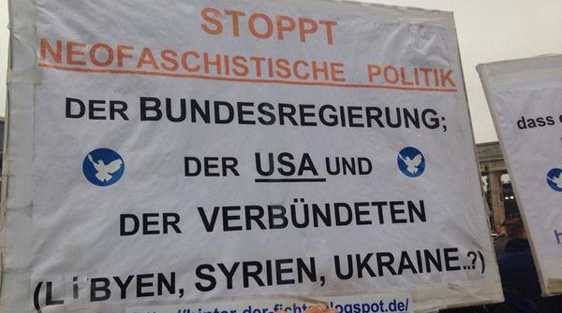 Un pacifista frente a la Puerta de Brandenburgo dice "Paremos a los políticos neo fascistas".