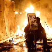 A demonstrator sits in front of a street fire during a demonstration in Oakland, California, following the grand jury decision in the shooting of Michael Brown.