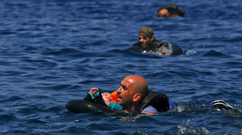 Un refugiado sirio sostiene a un bebé mientras nada hacia la orilla. Su embarcación auxiliar se desinfló antes de llegar a la isla griega de Lesbos. 