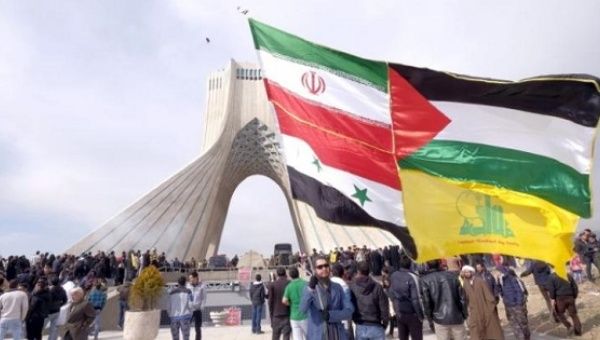 A man carries a giant flag made of flags of Iran, Palestine, Syria and Hezbollah, while marking the Islamic Revolution anniversary, Tehran, Feb. 11, 2016.