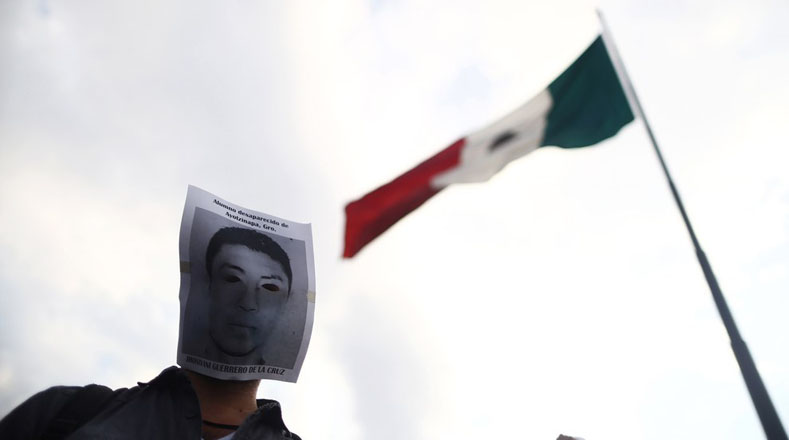 Con una foto en el rostro de uno de los desaparecidos, este hombre protesta en el Zócalo.