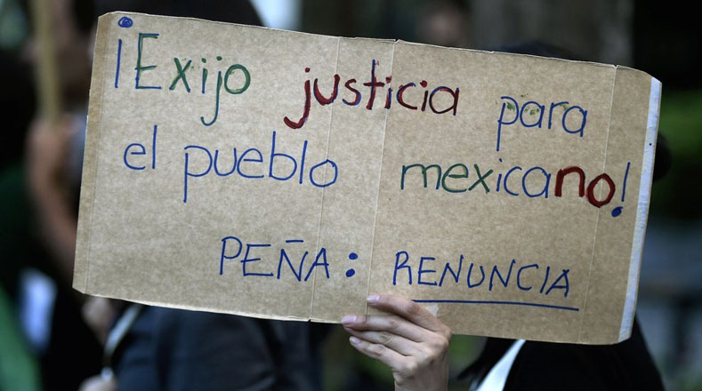Una mujer sostiene un cartel durante protestas en la Embajada de México en Buenos Aires.