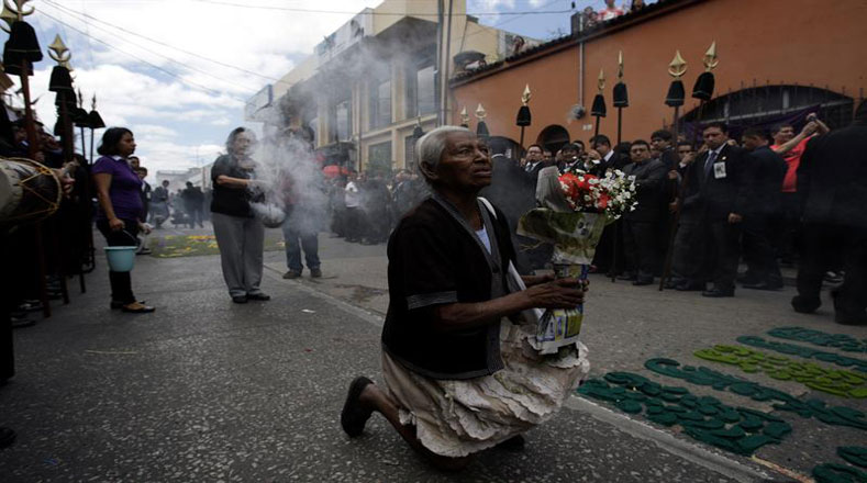 Una mujer se arrodilla ante el paso de "La Reseña", cortejo procesional de Semana Santa más antiguo de Guatemala.