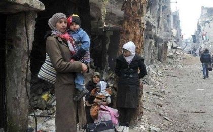 Una refugiada de Yarmouk, campamento palestino en Damasco, Siria, carga a su hijo en medio de una ciudad destrozada por los bombardeos 