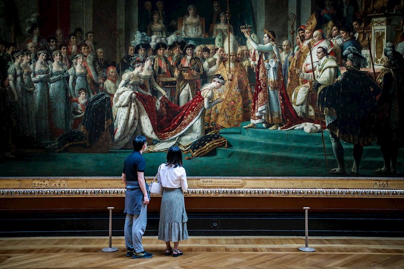 Frente al célebre cuadro de David sobre la coronación de Napoleón pasean dos visitantes en esta primera jornada de reapertura